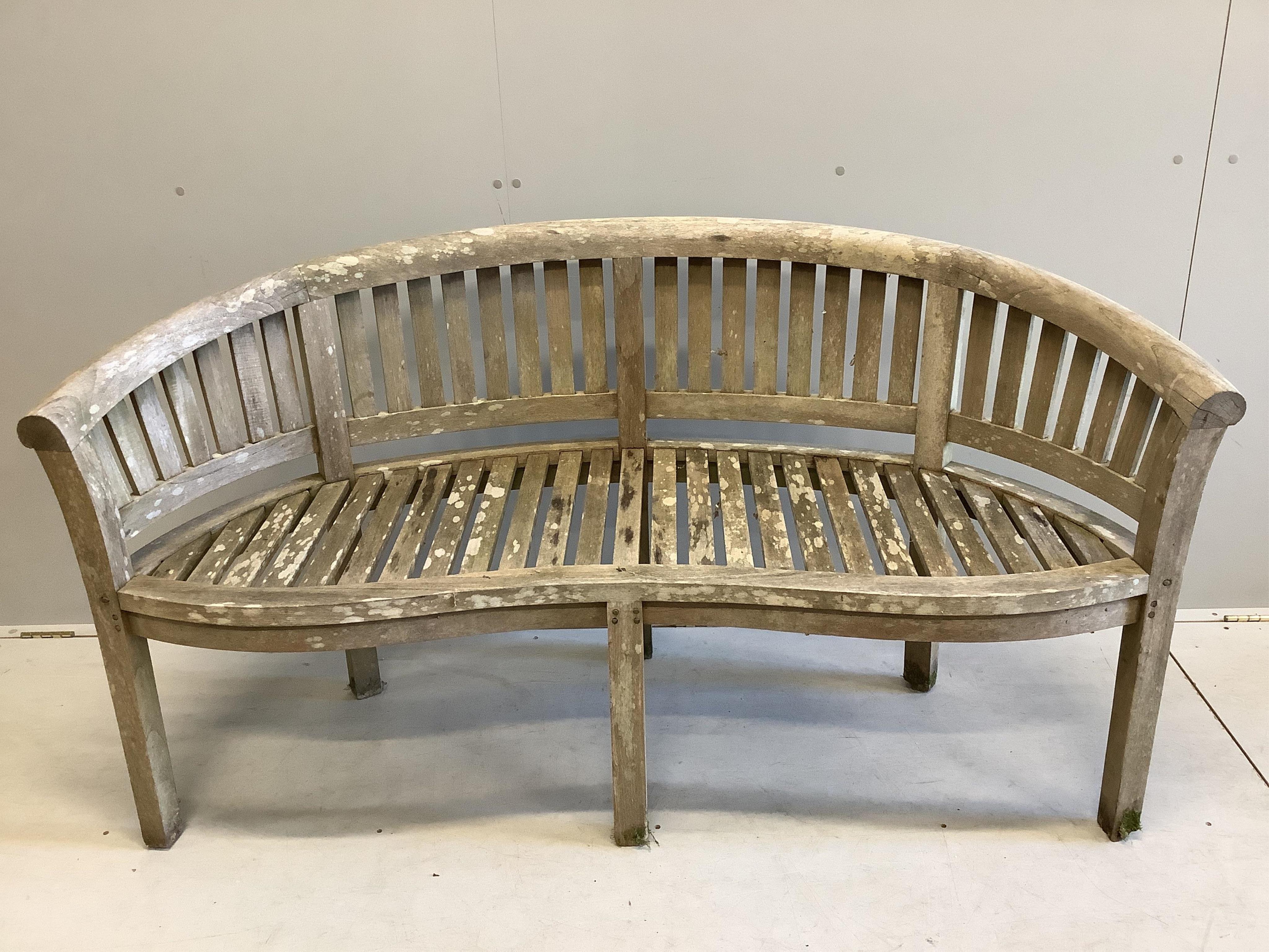 A weathered teak garden banana bench, width 150cm, depth 58cm, height 84cm. Condition -fair